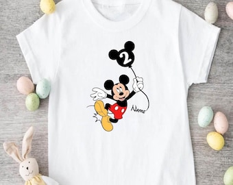 May include: White t-shirt featuring a black and red Mickey Mouse graphic holding a black balloon with the number 2 on it. The text "Name" is below Mickey Mouse.