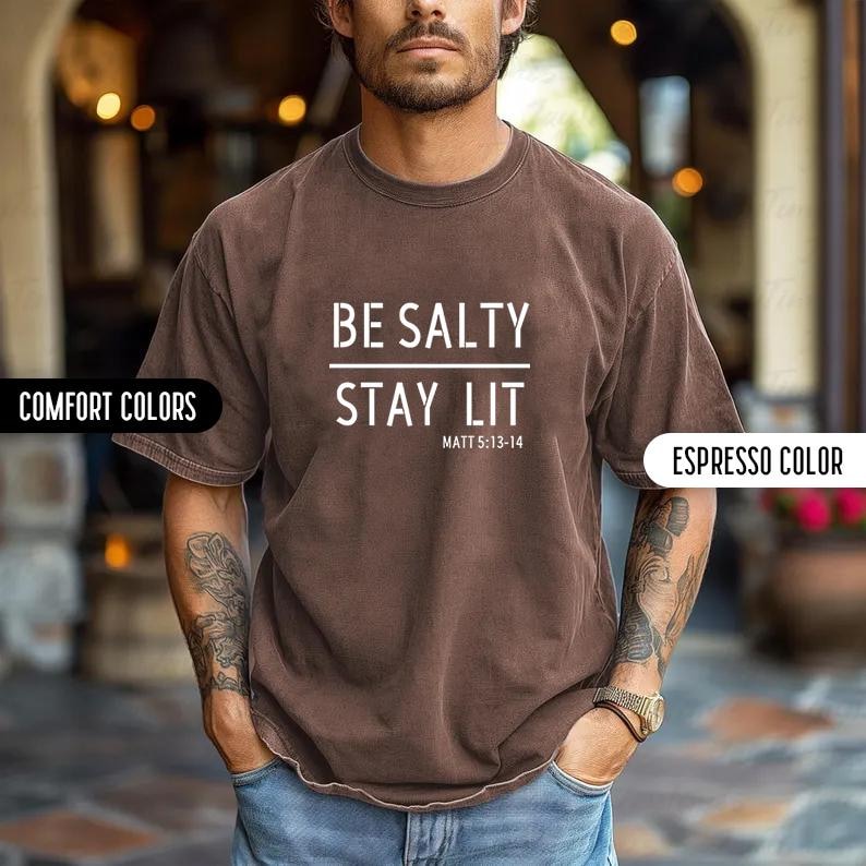 May include: A brown t-shirt with white text that reads "BE SALTY STAY LIT MATT 5:13-14".