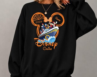 May include: A black long-sleeve sweatshirt featuring a large orange graphic of a Mickey Mouse ear outline containing a cruise ship with Disney characters, the text "Disney Cruise", "2026", and "Name" with a spiderweb and polka dot bow.