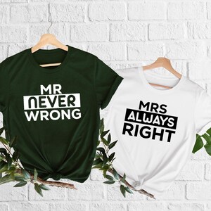 May include: Two t-shirts, one dark green and one white, hanging on wooden hangers. The dark green shirt has the text "MR NEVER WRONG" in white. The white shirt has the text "MRS ALWAYS RIGHT" in black.