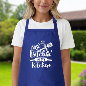 May include: Blue kitchen apron with white text that reads "No Bitchin' in my Kitchen" and a white silhouette of a rolling pin and whisk.