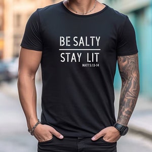 May include: Black t-shirt with white text that reads "BE SALTY STAY LIT" and "MATT 5:13-14"