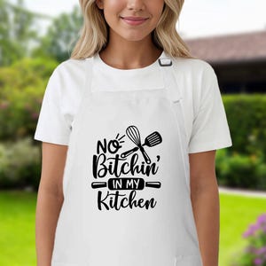 May include: White apron with black text that reads "No Bitchin' in my Kitchen" and a graphic of a whisk and spatula.