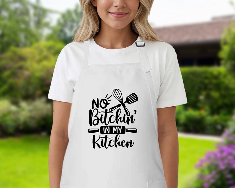 May include: White apron with black text that reads "No Bitchin' in my Kitchen" and a graphic of a whisk and spatula.