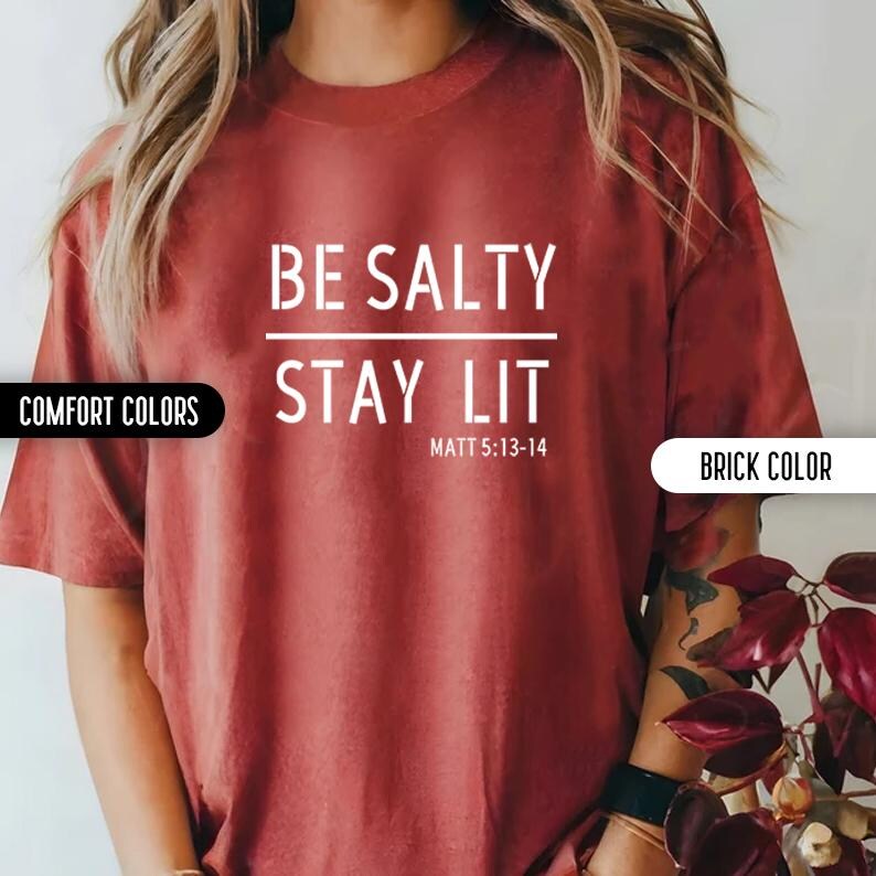 May include: A red t-shirt with the text "BE SALTY STAY LIT" and the scripture reference "MATT 5:13-14" in white text.