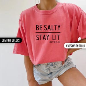 May include: A pink t-shirt with the text "BE SALTY STAY LIT" and the scripture reference "MATT 5:13-14".