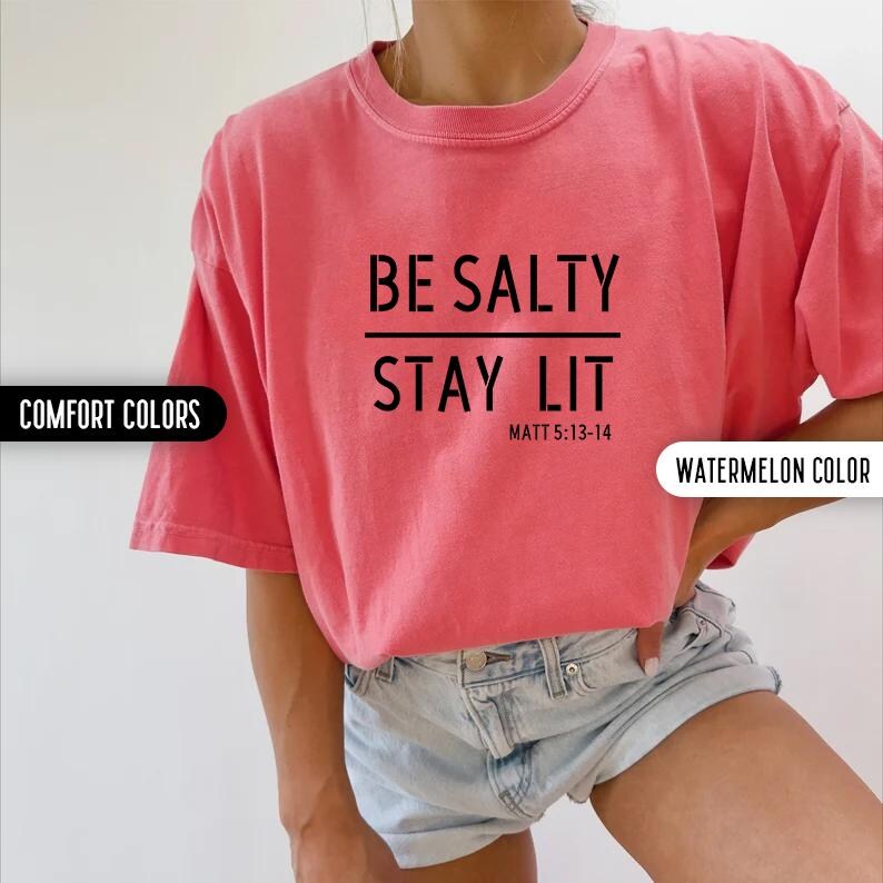 May include: A pink t-shirt with the text "BE SALTY STAY LIT" and the scripture reference "MATT 5:13-14".
