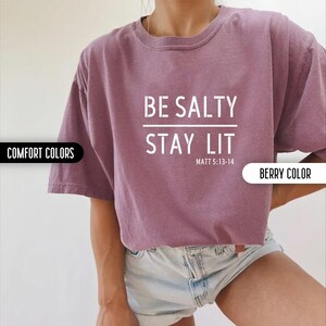 May include: A purple t-shirt with the text "BE SALTY STAY LIT" and the scripture reference "MATT 5:13-14" in white text.