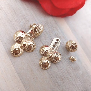 Peut inclure: Une paire de boucles d'oreilles dorées avec un design texturé et organique. Chaque boucle d'oreille présente quatre formes arrondies reliées.