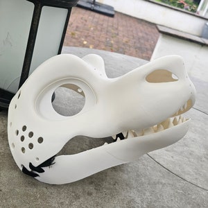May include: White furry mask with a detailed snout and teeth, featuring a large eye hole and a series of small holes on the side.