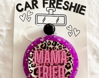 Könnte beinhalten: Lilafarbener Auto-Lufterfrischer mit Leopardenmuster und dem Text "Mama Tried" in rosa Buchstaben.