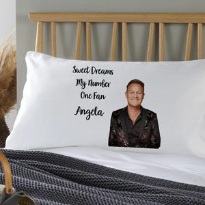 May include: White pillowcase with black text that reads "Sweet Dreams My Number One Fan Angela" and a photo of a man with short brown hair wearing a black sequined jacket.