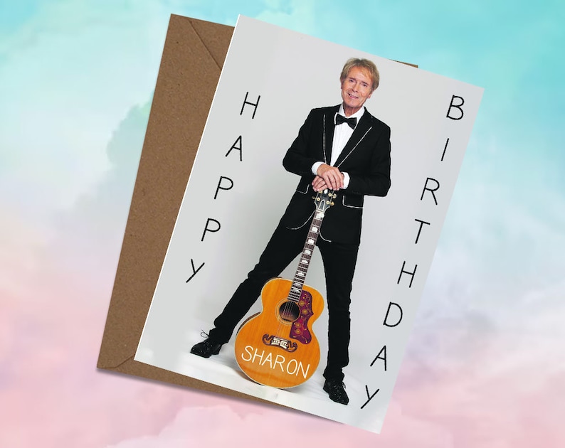 May include: A white card with a photo of a man in a black suit holding a guitar. The text "HAPPY BIRTHDAY SHARON" is written vertically on the card.