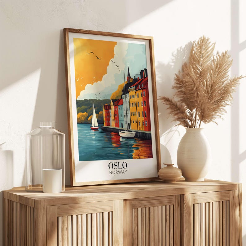 a framed poster of a scenic view of a harbor in Norway, with a sailboat and buildings in the background. The poster is displayed on a wooden shelf, accompanied by a vase of dried flowers and a glass jar.