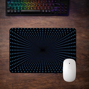 Può includere: Tappetino per mouse nero con un motivo a stella blu e un mouse wireless bianco. La tastiera ha luci a LED multicolore. Il tappetino è rettangolare e si trova su una superficie di legno.