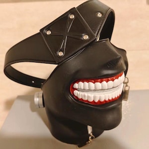K&ouml;nnte beinhalten: Schwarze Ledermaske mit einem Rei&szlig;verschluss-Mund und einem wei&szlig;en Kreuzdesign auf der Stirn. Die Maske ist ein beliebter Charakter aus der Anime-Serie Tokyo Ghoul.