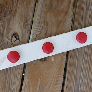 May include: White wooden coat rack with three red knobs.