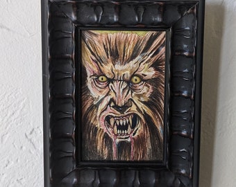 May include: A framed drawing of a werewolf with yellow eyes and sharp teeth. The werewolf is depicted in a snarling expression with a bloody mouth.