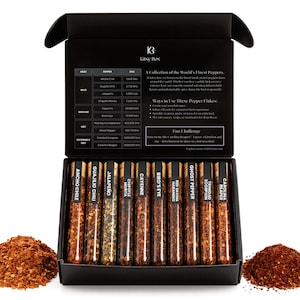 May include: A black gift box containing ten glass vials of dried pepper flakes, each labeled with a different pepper type. The box also includes two small piles of pepper flakes. The text on the box reads "Kitsy Box".