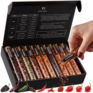 May include: A black box set of gourmet pepper flakes, including Ancho Chili, Cayenne, and Carolina Reaper. Each pepper is in a glass vial with a cork stopper. The box includes a heat level chart and usage suggestions.
