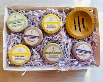 May include: A white gift box filled with six round shower steamers in various colors and scents, including eucalyptus mint, lavender chamomile, and lemon ginger. The box also includes a small bamboo soap dish.