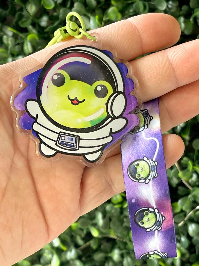 Pu&ograve; includere: Un portachiavi in plastica trasparente con una rana verde vestita da astronauta e un design a galassia viola e bianco. Il portachiavi &egrave; dotato di un laccio a galassia viola e bianco abbinato con un'immagine ripetuta della rana astronauta.