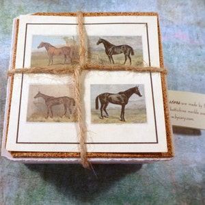 May include: Set of four cork-backed coasters featuring vintage illustrations of horses. The coasters are tied together with twine and have a brown border around each image. The text on the tag reads "Coasters are made by Cary using botticino marble and the finest materials. www.bycary.com."