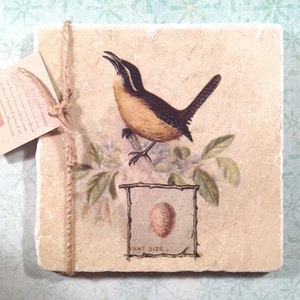 May include: A beige square tile with a brown bird illustration. The bird is perched on a branch with green leaves. The tile has a brown border and the text "NAT SIZE" below the bird.
