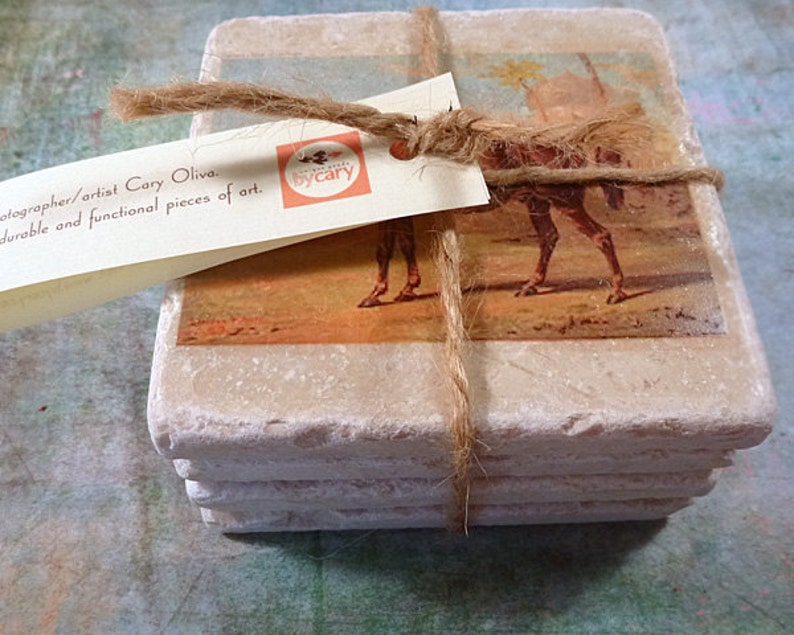 May include: Set of four square stone coasters with a vintage image of a camel printed on each. The coasters are tied together with twine and a tag that reads "The Works by Cary".