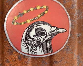 May include: A sticker with a detailed black and white illustration of a bird's skull with a halo of yellow flowers and green leaves. The background is a solid red color.