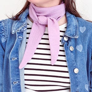 May include: A light purple scarf tied around the neck. The scarf is made of a soft, textured fabric. The person is wearing a striped shirt and a denim jacket with heart-shaped designs.