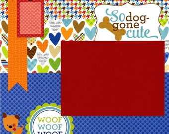 May include: A scrapbook page with a red, white, and blue color scheme. The page features a dog-themed design with hearts, paw prints, and the text "So dog-gone cute".