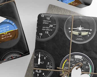 May include: Black wrapping paper featuring a repeating pattern of various aircraft cockpit instruments, including airspeed indicators, altimeters, and vertical speed gauges with white text and colorful accents, tied with twine and white paper tags.
