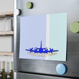 May include: A rectangular magnet featuring a light blue and white vertical striped background. A dark blue silhouette of a P-3 Orion aircraft is centered, with the gold text P-3 Orion Naval Air Veteran printed directly underneath the aircraft graphic.