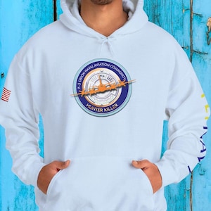 May include: White hooded sweatshirt with a navy blue, orange, and white graphic on the front. The graphic includes the text "P-3 Orion Naval Aviation Community" and "Hunter Killer". The left sleeve has a small American flag.
