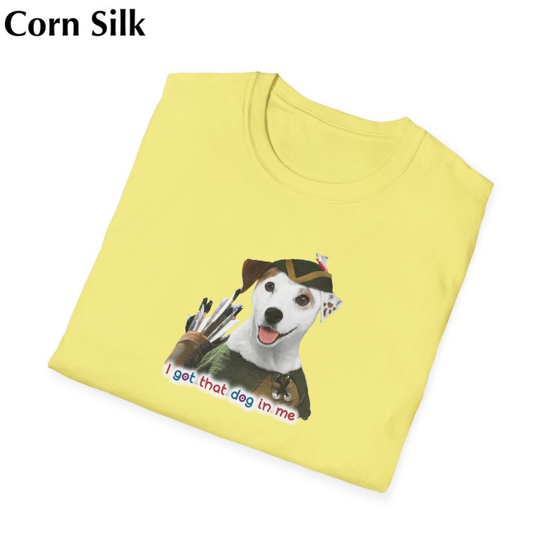 May include: Corn Silk yellow t-shirt featuring a cartoon dog dressed as an archer with a quiver of arrows. The dog wears a green and brown outfit and a hat. The text "I got that dog in me" is printed below the dog.
