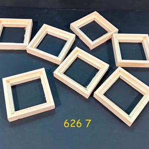 May include: A collection of seven square wooden frames arranged in a scattered pattern. Each frame is constructed from light-colored, unfinished wood with visible joints at the corners. The yellow text 626 7 is printed at the bottom center.
