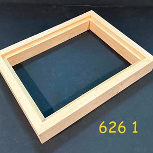 May include: A rectangular light-colored wooden picture frame with a stepped inner edge profile. The frame has a natural wood grain finish and a clean, unpainted surface. The yellow text 626 1 is visible in the lower right corner of the image.