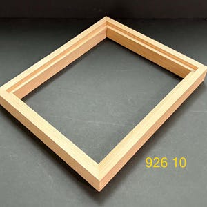 May include: A rectangular light-colored wooden picture frame with a stepped inner edge profile. The frame is constructed from natural wood with visible grain patterns. The yellow text 926 10 is printed in the lower right corner of the image.