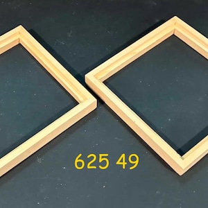 May include: Two square, light-colored wooden frames with a natural finish and a recessed inner edge. The frames are positioned diagonally on a dark surface. The yellow text 625 49 is printed between the two frames, indicating a specific model.