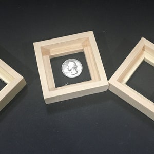 May include: Three wooden picture frames of different sizes. The middle frame has a quarter inside.
