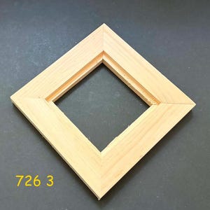May include: A square wooden frame with a light natural finish, positioned in a diamond orientation. The frame features mitered corners and an inner recessed ledge for mounting. The yellow text 726 3 is visible in the lower left corner.
