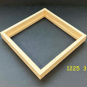 May include: A square, wooden frame with a natural finish. The frame is made of light-colored wood and has a simple, clean design. The dimensions are not visible. The numbers "1225 32" are printed in yellow in the bottom right corner.