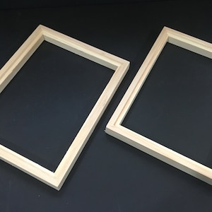 May include: Two wooden picture frames, both with a natural wood finish. The frames are rectangular and have a simple, classic design.