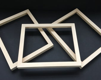 May include: Three unfinished wooden picture frames of different sizes, stacked on top of each other. The frames are made of natural wood and have a smooth finish.
