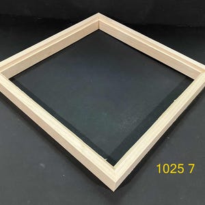 May include: A square, light-colored wooden picture frame with a beveled inner edge and a flat outer profile. The frame is empty, showing a clean, natural wood grain finish. The yellow text 1025 7 is visible in the bottom right corner of the image.