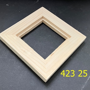 May include: A natural wood, diamond-shaped frame with a recessed inner edge. The frame is made of light-colored wood and is positioned on a dark surface. The number "423 25" is printed in yellow on the bottom right corner.
