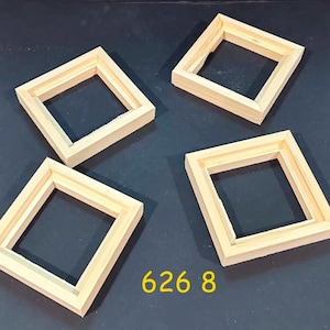 May include: Four square, light-colored wooden frames with mitered corners and a recessed inner edge. The frames are arranged in a scattered pattern, and the yellow text 626 8 is visible at the bottom center of the composition.