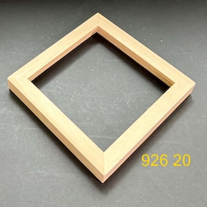 May include: A square wooden picture frame with a light natural wood grain finish. The frame features mitered corners and a simple, flat profile. The yellow text 926 20 is printed in the lower right corner of the frame's surrounding area.