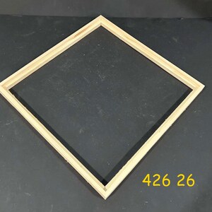 May include: A square wooden picture frame with a light natural finish, positioned at a diamond angle. The frame features mitered corners and a simple profile. The yellow text 426 26 is visible in the lower right corner of the image area.